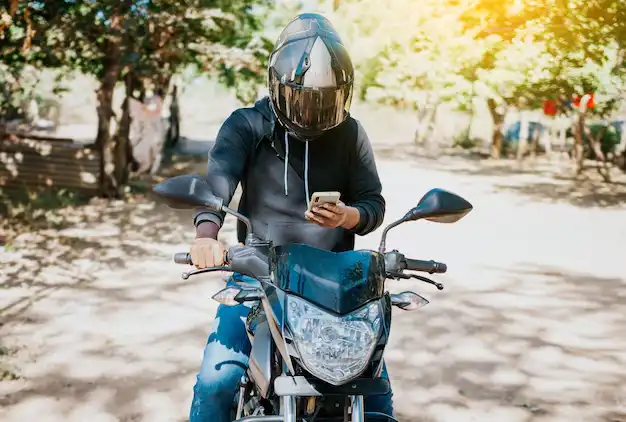 man motorbike texting while driving motorcyclist motorcycle using cell phone outdoors concept distracted motorcyclist with cell phone